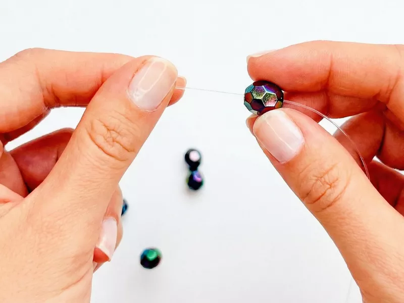 Pessoa fazendo bijuterias com contas coloridas