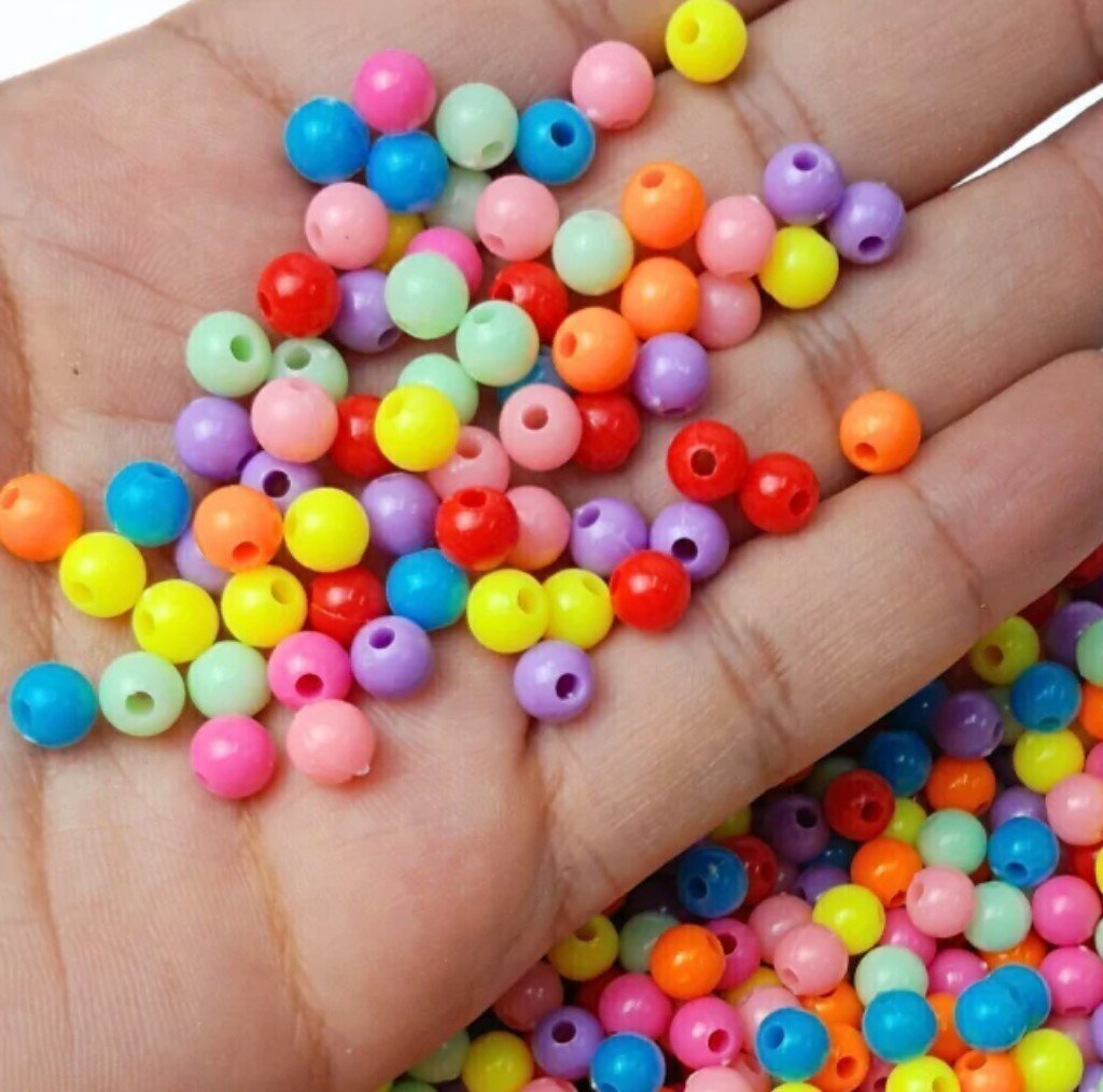 Miçangas coloridas de plástico em uma mão.