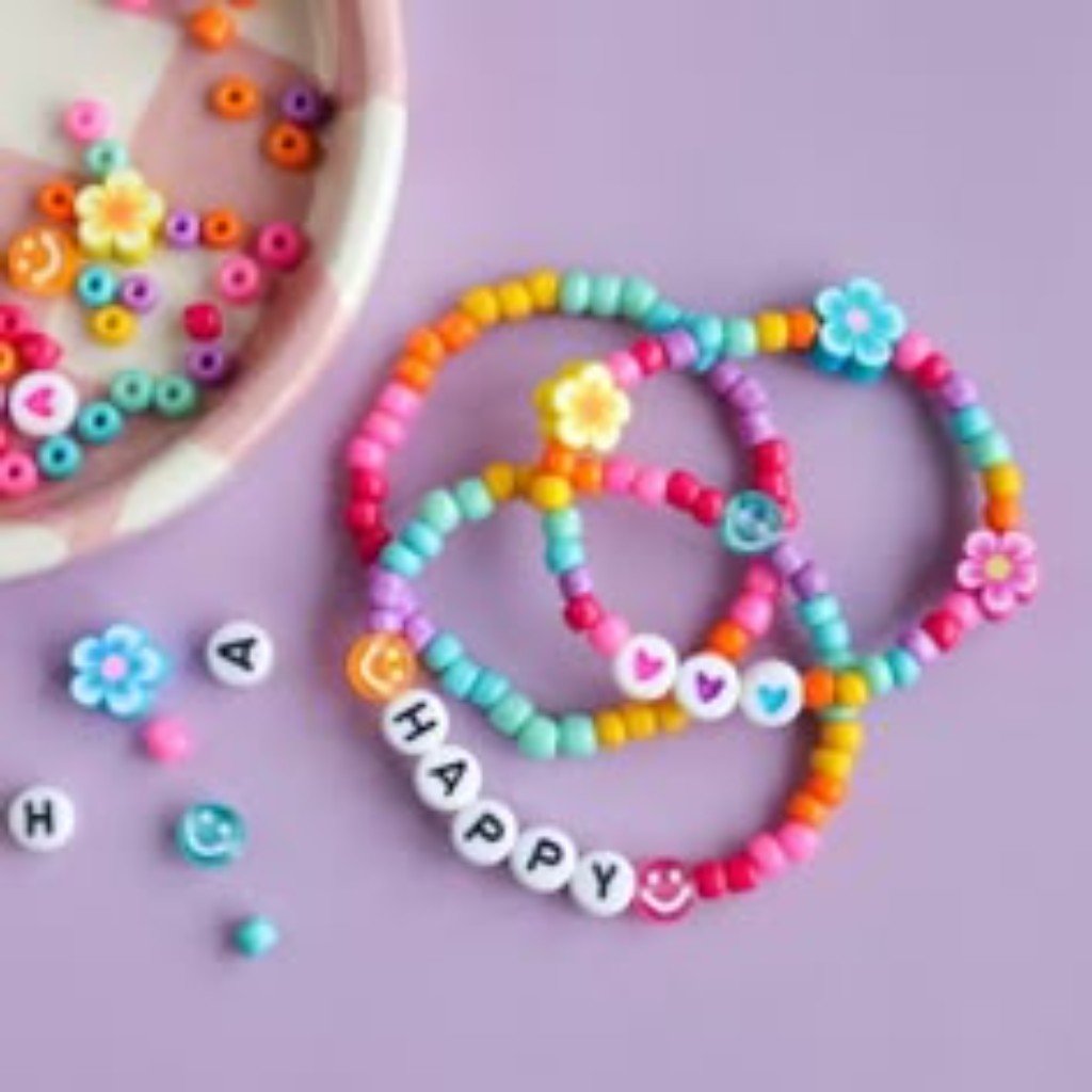 Três pulseiras artesanais coloridas com miçangas, um sorriso e a palavra HAPPY.
