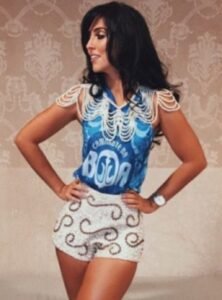 Mulher com uma blusa de carnaval azul e uma saia de shorts brancos bordada.