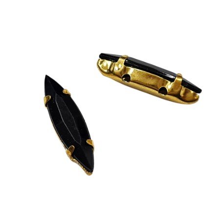 Dois chatons pretos em forma de navete com engastes de metal dourado, em um fundo branco.