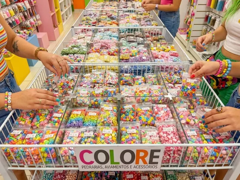 Mesa cheia de pedrarias coloridas e acessórios artesanais.