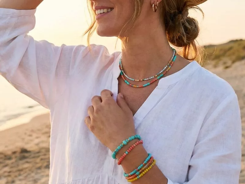 Mulher com colares e pulseiras coloridas na praia