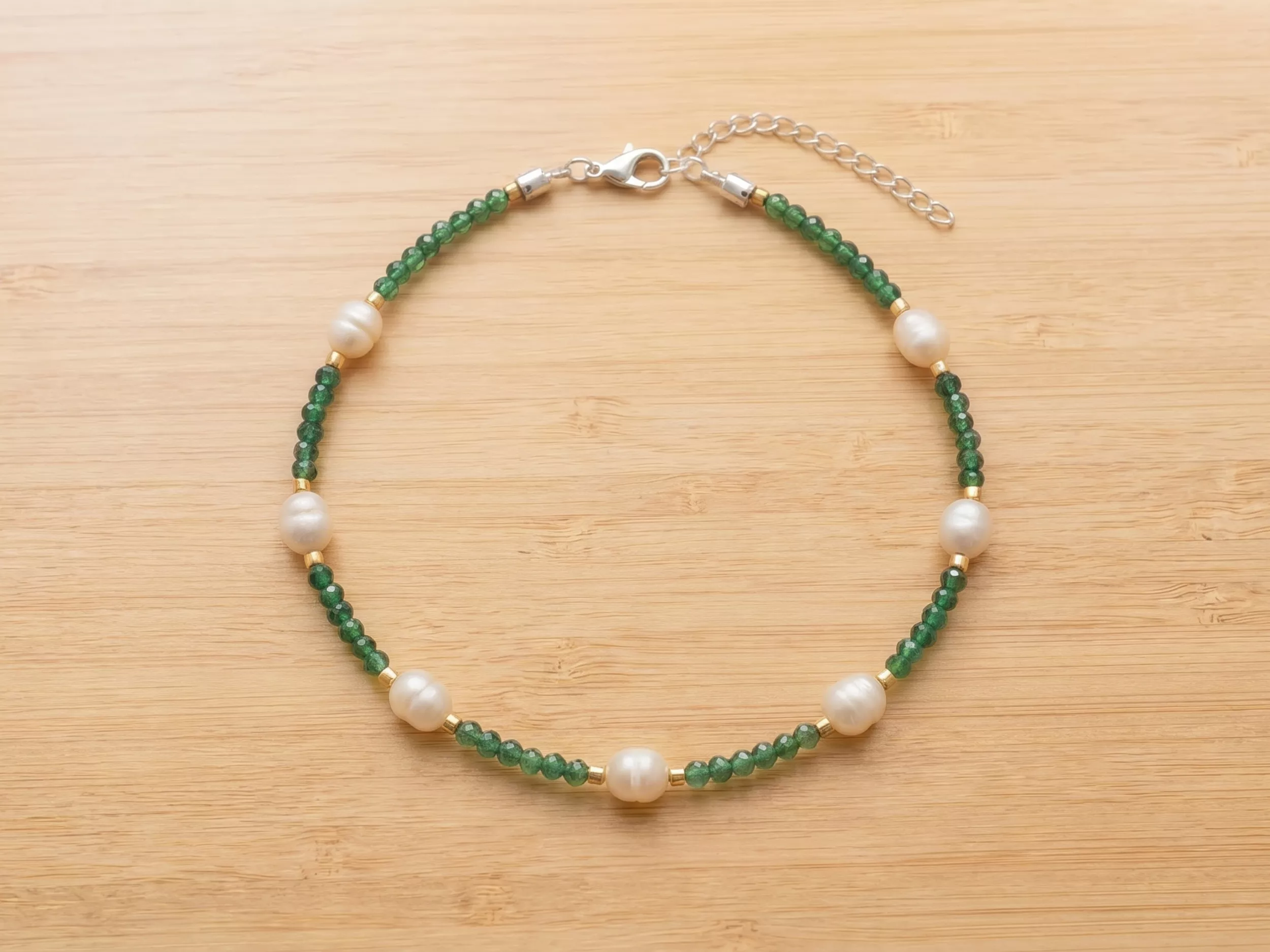 Colar de pérolas e pedras verdes em mulher sorridente
