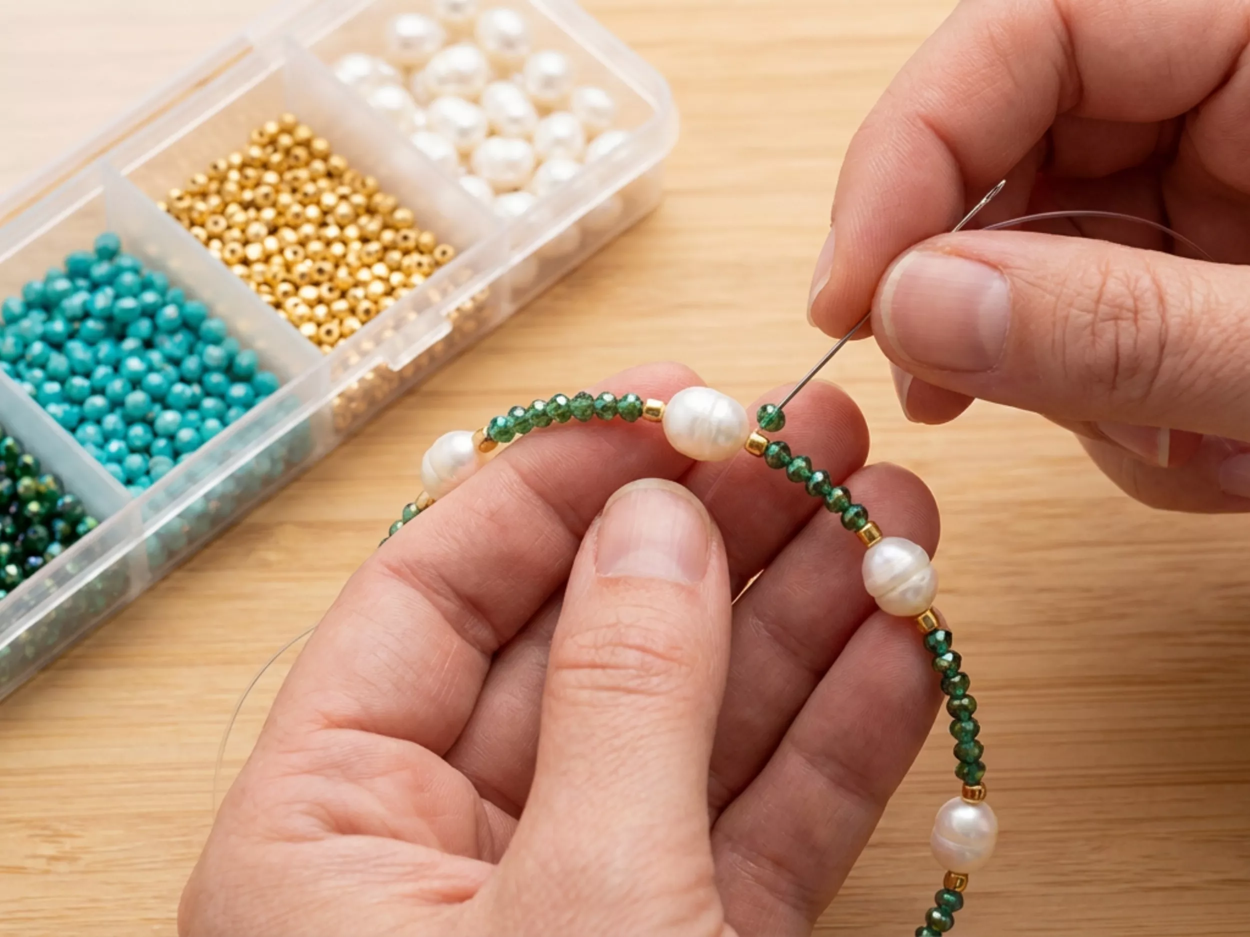 Pessoa fazendo colar com pérolas e miçangas coloridas
